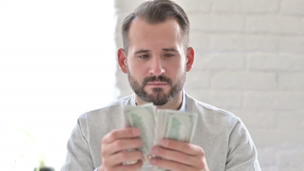 Портрет ориентированного молодого человека, считающего доллары — стоковое видео