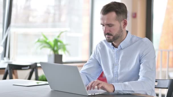 Jeune homme malade avec ordinateur portable tousse dans le bureau — Video