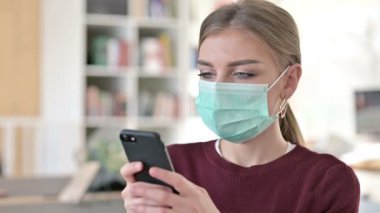 Akıllı telefon kullanan Yüz Maskeli Genç Kadın Portresi