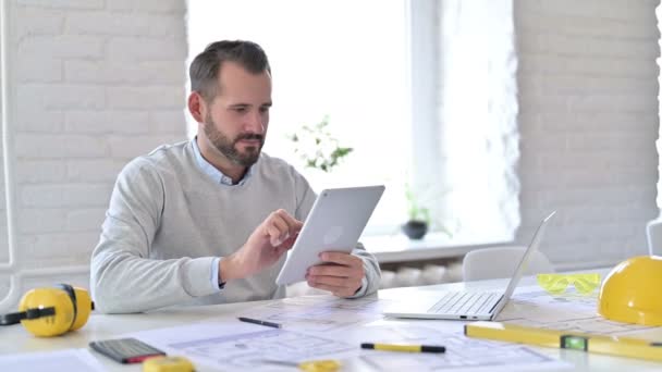 Młody architekt świętuje sukces na tablecie w biurze — Wideo stockowe