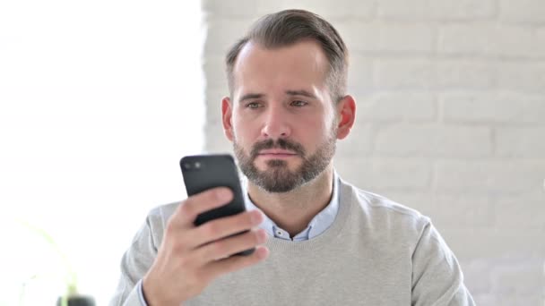 Retrato del joven arquitecto celebrando el éxito en Smartphone — Vídeo de stock