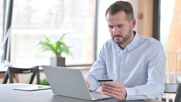 Niedokonanie płatności online przez młodego człowieka na laptopie w biurze — Wideo stockowe