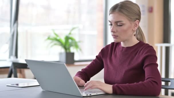 Επαγγελματική νεαρή γυναίκα που χρησιμοποιεί φορητό υπολογιστή στο γραφείο — Αρχείο Βίντεο
