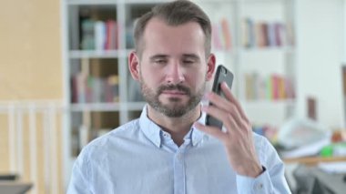 Smartphone 'da konuşan gülümseyen genç adamın portresi