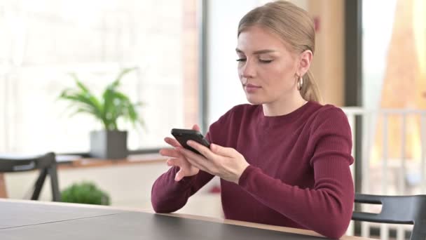 Молода жінка розмовляє по смартфону в офісі — стокове відео