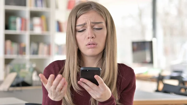 Jovem mulher reagindo a perda no smartphone — Fotografia de Stock
