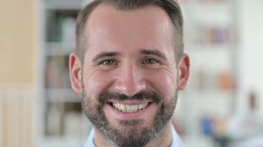 Kameraya gülümseyen genç adama yakın çekim