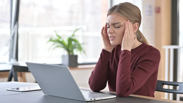 Młoda kobieta z bólem głowy za pomocą laptopa w biurze — Zdjęcie stockowe