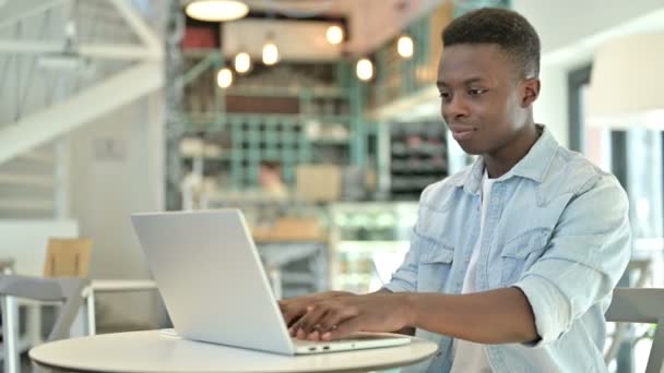 Cafe 'de dizüstü bilgisayarda çalışan neşeli bir Afrikalı. — Stok video