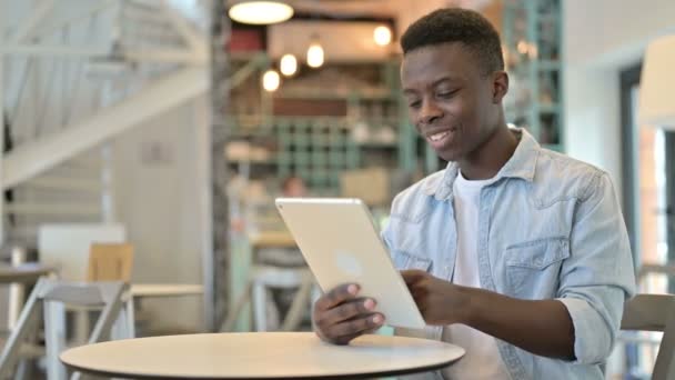 Glada ung afrikansk man som arbetar på Tablet i Café — Stockvideo