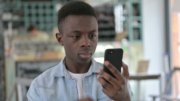 Retrato de un joven africano celebrando el éxito en Smartphone — Vídeo de stock