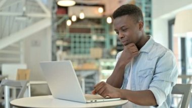 Kafe 'de laptopta düşünen ve çalışan dalgın bir Afrikalı.