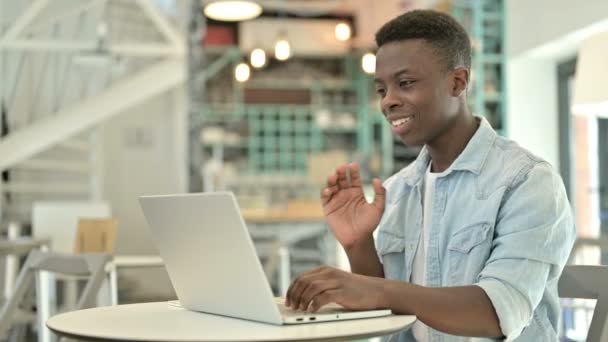 Молодой африканский человек делает видео-чат на ноутбуке в кафе — стоковое видео