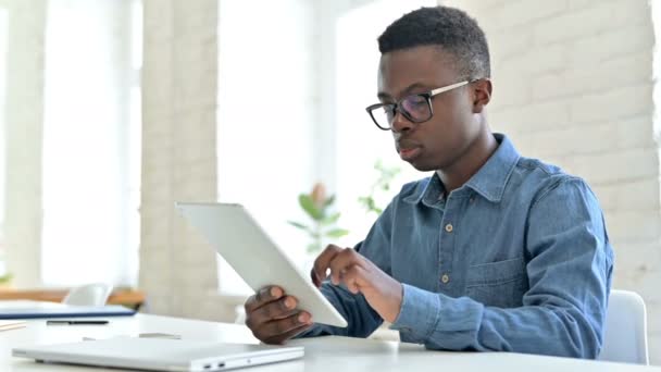 Fröhlicher junger Afrikaner arbeitet an Tablet — Stockvideo