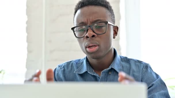 Retrato de un joven africano decepcionado reaccionando a la pérdida en el ordenador portátil — Vídeos de Stock