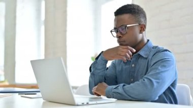 Genç Afrikalı Adam laptopta düşünüyor ve çalışıyor.