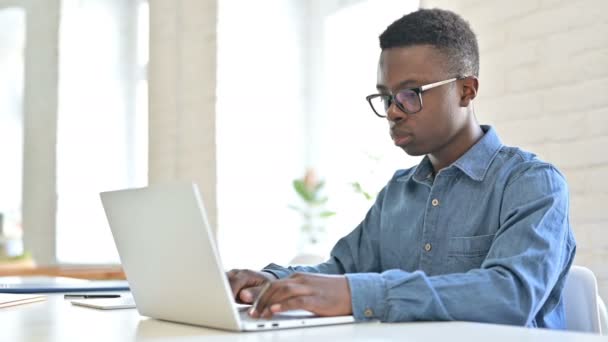 Verontruste jonge Afrikaanse man reageert op verlies op laptop — Stockvideo