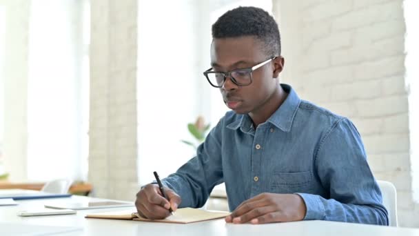 Серйозний молодий африканський чоловік робить папери в офісі — стокове відео