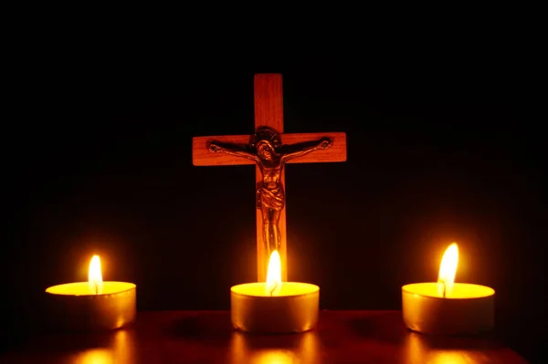 Crucifixo e três velas acesas na escuridão. Rezai a Jesu — Fotografia de Stock