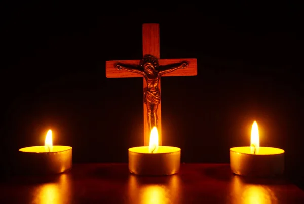 Crucifixo e três velas acesas na escuridão. Rezar e pular — Fotografia de Stock