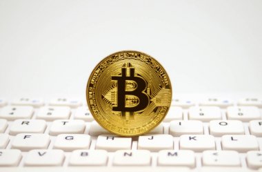 Bitcoin beyaz klavye üzerinde sembolik altın sikke
