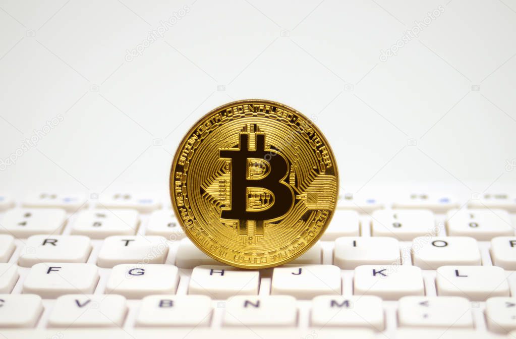 Golden symbolic coin of bitcoin on white keyboard