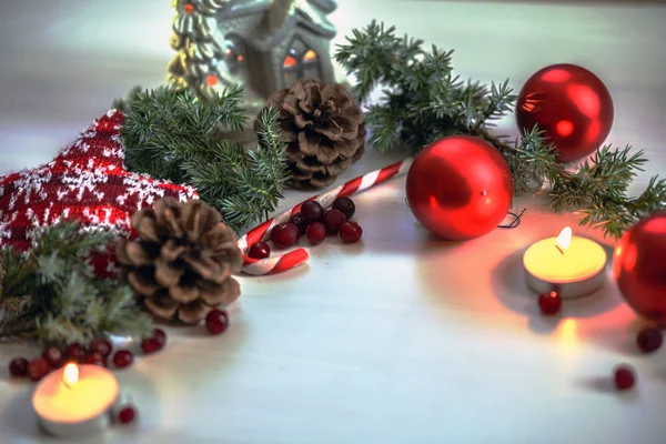 Kerst samenstelling op houten achtergrond rode ballen, geschenken en groene kerstboom tak met kegels, brandende kaars — Stockfoto