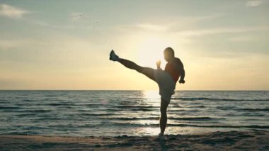 güçlü adam gün batımında sahilde boks