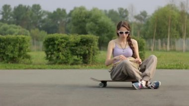 kaykay üzerinde poz ve telefonunuzun ve bir genç kadın