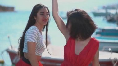 İki kadın kırmızı elbiseler içinde yat iskelede dans