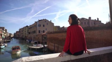 Venedik'te köprünün üzerinde oturan romantik kadın