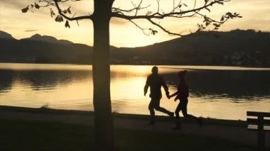 Göl günbatımı sırasında çalışan çift siluetleri