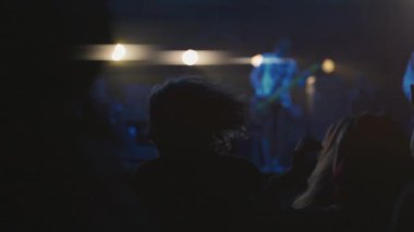 Açık hava rock konserinde dans eden hayranların aydınlatılmış silueti. İnsanlar dışarıdaki müzik festivalinde kapışıyorlar. Kalabalık gece konserinde şarkı dinleyip alkışlıyor. Eğlence ve kültür konsepti.