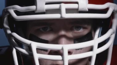 Miğferli kararlı Amerikan futbolcusunun portresi. Gözlerinizi kapayın. Üniformalı, kendinden emin ve agresif bir adam. Erkeksi futbolcu. Usa takım oyunu ve ekstrem spor, yarışma.