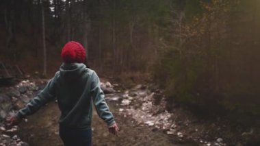 Yalnız genç melez kadın bakir sonbahar ormanlarında el kaldırıyor. Derin özgürlük kavramı soluyun. Mutlu karantina hayatı yalnızlık ve yalnızlık. Doğayla bir araya gelme. Vahşi doğada şapka yürüyüşü yapan kız