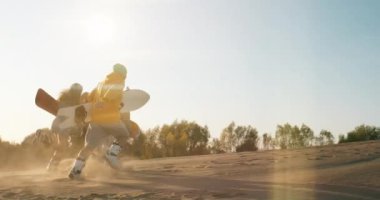 Üç neşeli çok ırklı arkadaş yaz tatilinin tadını çıkarıyor. Genç hippi adamlar ellerinde kumla gün batımında yüksekten koşuyorlar. Tatiller, spor, yolculuk, seyahat, mutluluk, arkadaşlık konsepti.