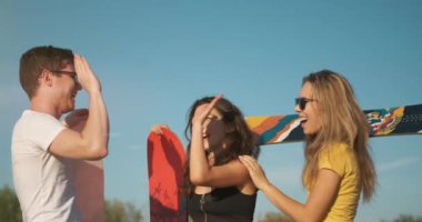 Açık havada yaz. Mutlu gülümseyen insanlar, ellerinde snowboard ile güneşli bir gecede beş kez arka planda bulunuyorlar. Çölde kum kaykayı. Genç arkadaşlar buluşuyor. Tatil, turizm ve ekstrem spor konsepti.