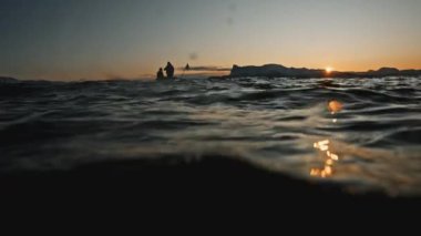 Dalgıçlar, deniz ve Norveç fiyortlarıyla çevrili gün batımında teknede oturuyorlar. Romantik bir yolculuk, dalgalara binmek. Norveç 'e bilimsel keşif gezisi sırasında RED' de çekilen özel belgesel görüntüleri