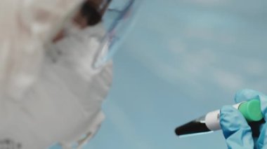 Cam tüpte kan testine bakan mavi ameliyat eldivenleri giyen mikrobiyolog ya da tıp çalışanına yakın çekim. COVID-19, koronavirüs, pandemik konsept. Tıp laboratuarındaki bilim adamı deney yapıyor..