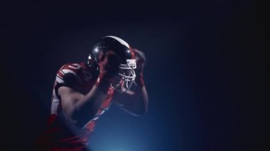 Kasklı kararlı Amerikan futbolcusunun portresi topu izole edip kaçtı. Erkeksi yaşam tarzı. Üniformalı kendinden emin bir adam. Usa takım oyunu ve ekstrem spor ruhu konsepti.