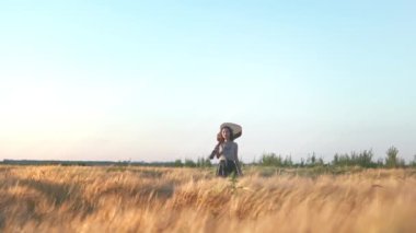 Sinematik hippi kız elinde gitarla buğday tarlasında yürüyor. Akustik enstrümanlı kadın doğanın ve güneş ışığının tadını çıkarıyor. İnsanlar, yaşam tarzı, öğrenci, ifade ve tarz kavramı