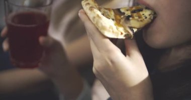 Pizza yiyen ergen bir kızın yakın çekimi. Gençlik, arkadaşlık, milenyum, abur cubur, yaşam tarzı konsepti. RED 4k, 12 bit renk alanı.