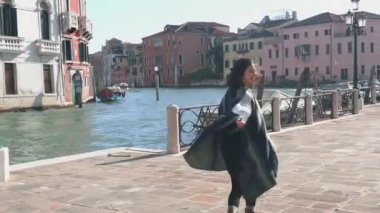 Venedik 'in dar sokaklarında yürüyen çizgili pançolu şık Asyalı kadın. Ateşli esmer tilki deniz kenarında romantik bir yürüyüş için işaret ediyor. Seyahat kavramı.