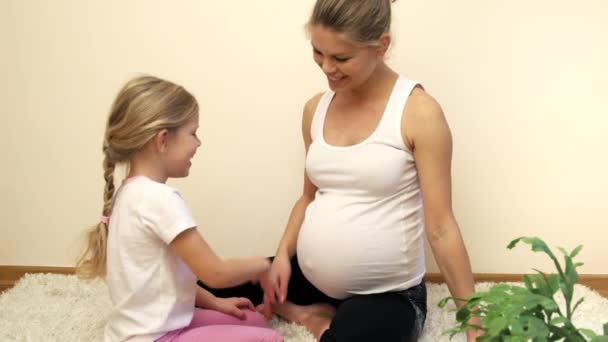 彼女の腹に触れる彼女の小さな娘と一緒に床に座って幸せな妊娠中の女性 — ストック動画