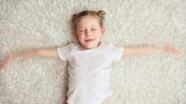 Sevimli oynak kız hayal sinek, kapalı halı üzerinde yalan. Sevimli küçük kız evde eğlenmek.