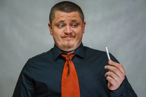 A young man posing with an unlit cigarette in his hand. The man is thoughtful and surprised. No smoking. — Stock Photo, Image