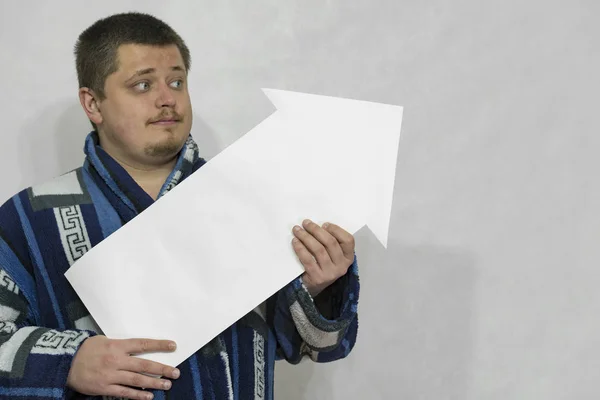 Um homem de vestido com uma seta de papel branco ou ponteiro em suas mãos . — Fotografia de Stock
