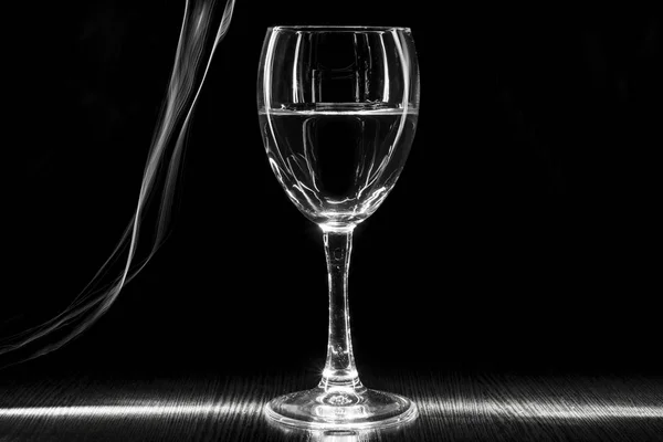 Egy átlátszó pohár bor folyadékkal. Fehér csíkok a fekete háttér életlen. — Stock Fotó