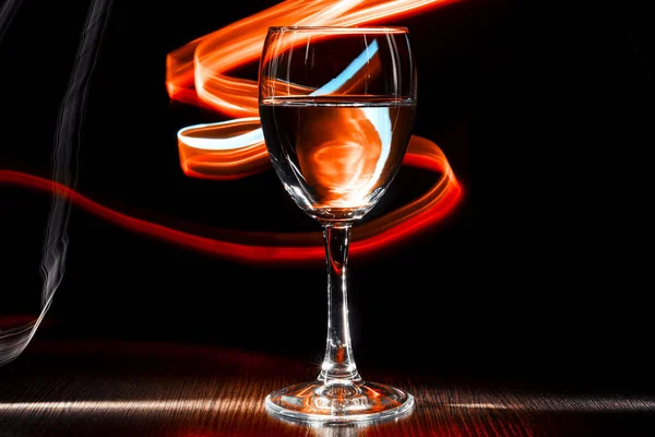 Şeffaf bir kadeh şarap ile bir sıvı. Kırmızı ve turuncu bulanık bantları. — Stok fotoğraf