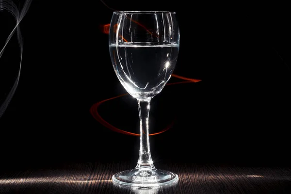 Ett genomskinligt glas vin med en vätska. Ljuseffekt. — Stockfoto